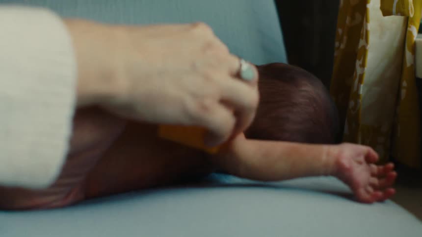 Hand with a sponge bathing a newborn baby