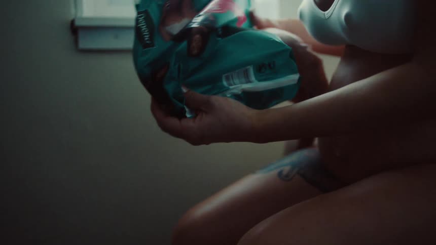 Pregnant woman sitting down picking up a diaper