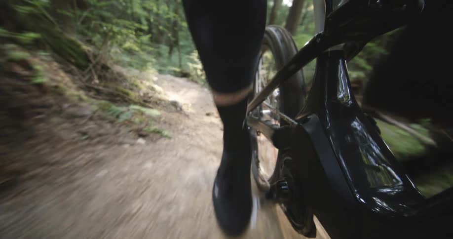 Close up of a persons feet riding a mountain bike in a forest
