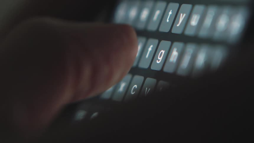 A persons fingers are pressing the keys of a small keyboard with white letters