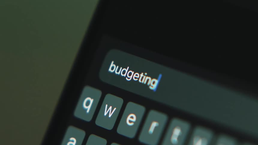 White letters are on a small keyboard as someone types budgeting