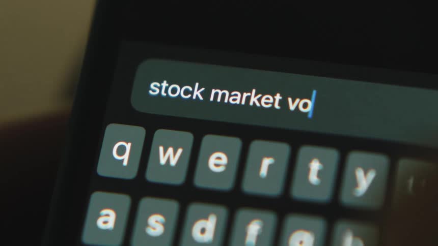 Letters glow on a small keyboard as someone is typing stock market volatility