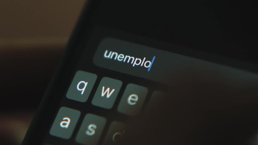 Letters glow on a keyboard as someone types and searches for unemployment