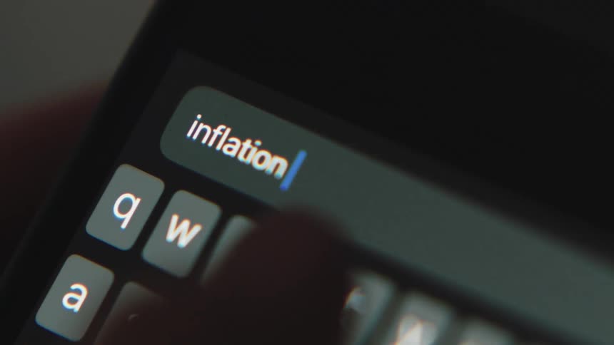 Close up of persons hand texting inflation on smartphone
