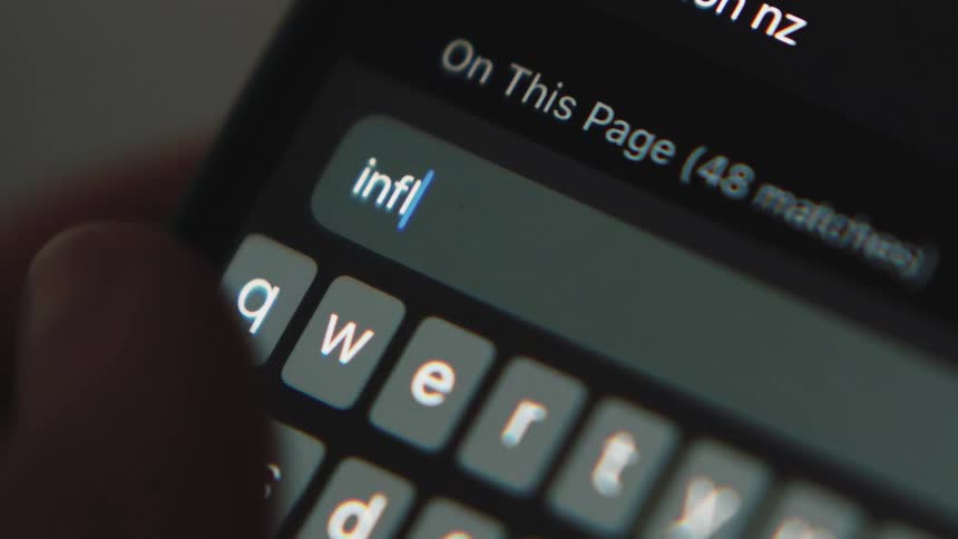 White letters are on a small keyboard as someone types inflation right now