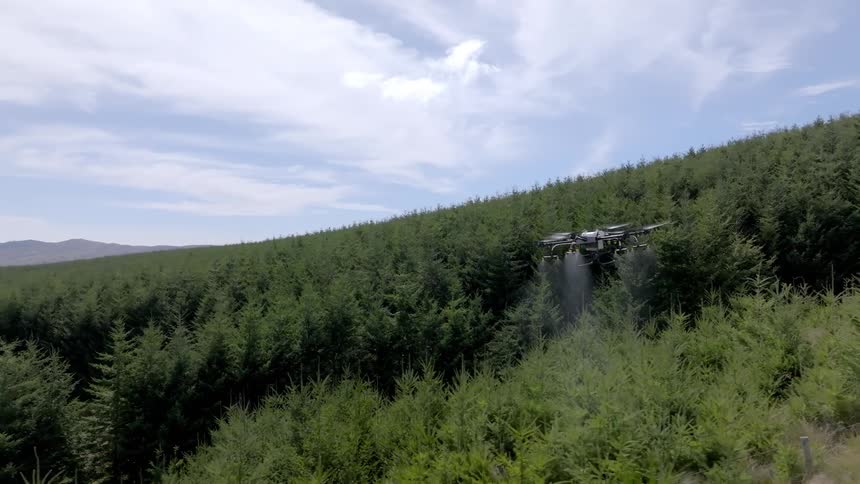 A large UAV drone disperses product onto a forest