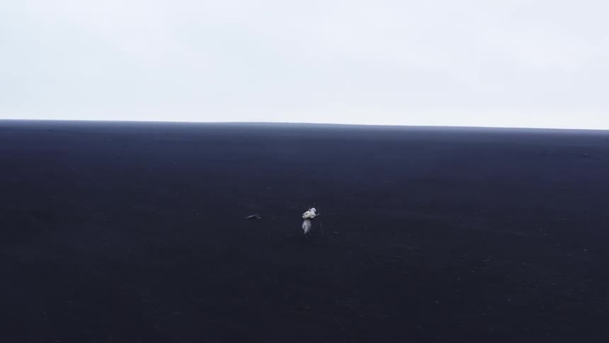 Person dressed in white walks alone in a vast field of cooled lava