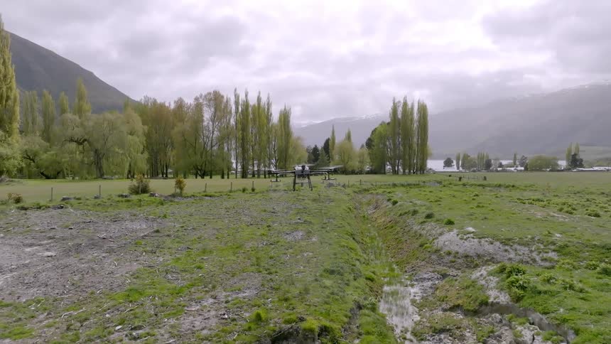 Drone hovers over a swamp in front of the mountains
