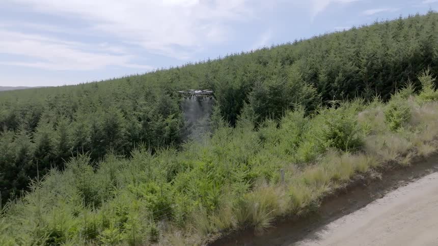 Commercial drone pouring water on trees next to forest