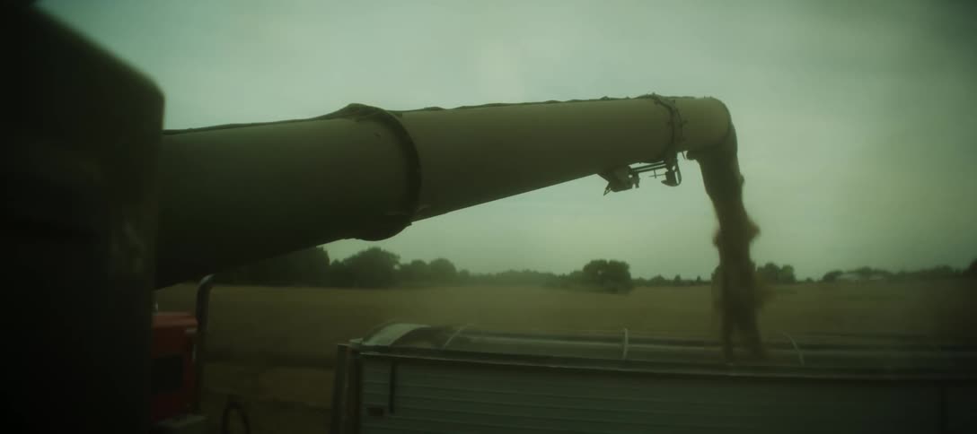 A giant harvester fills a container with grain on a farm