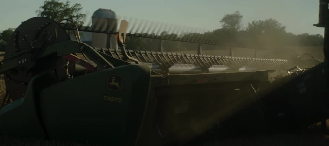 Agricultural machine moves across a crop field on a farm on a cloudy day