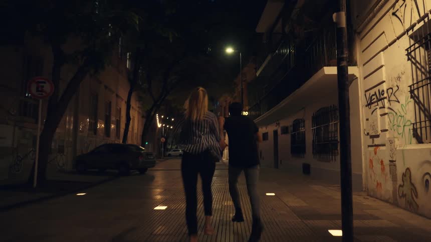 A man and a woman run down a city street at night