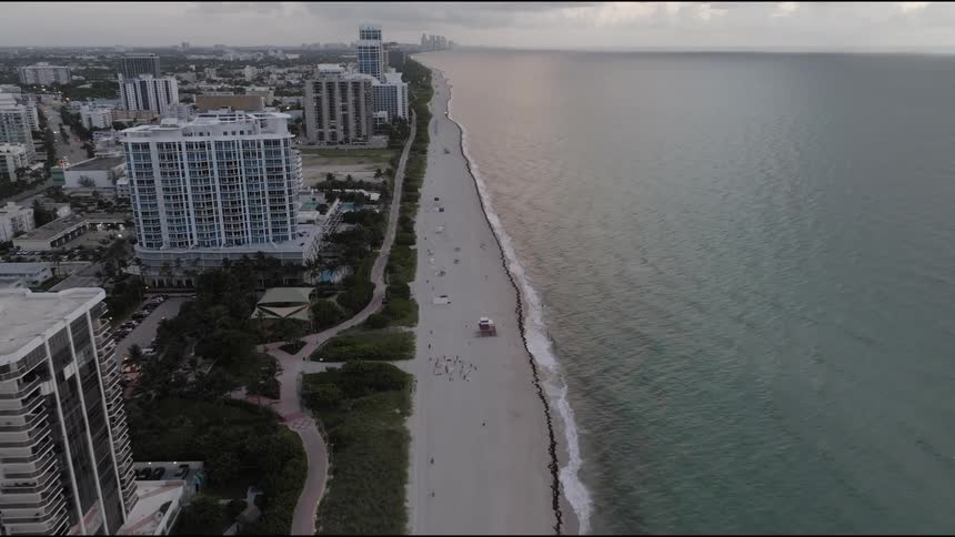 People gather on a beach located right next to large city buildings