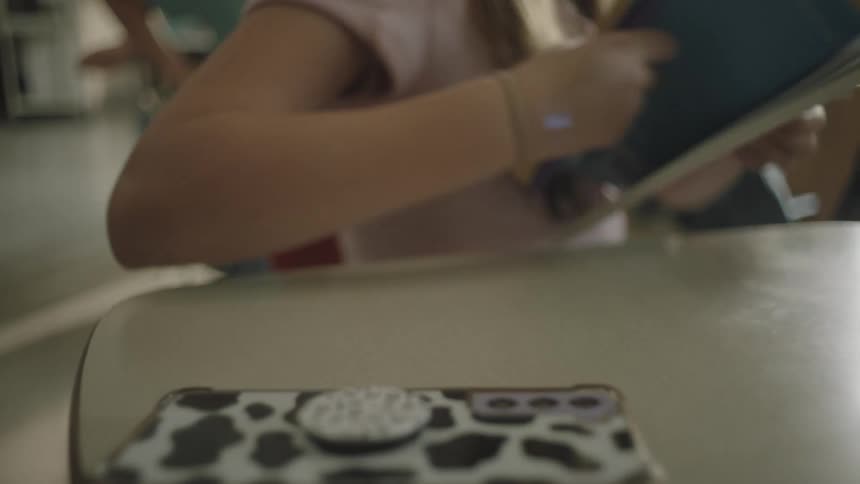 A young woman in class slams her study book shut and gets up from her desk