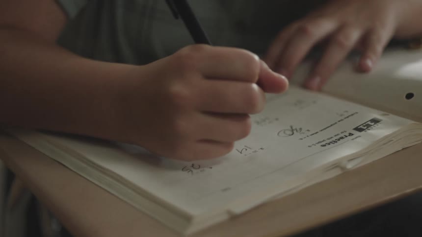 Close up of a childs hands writing in a book