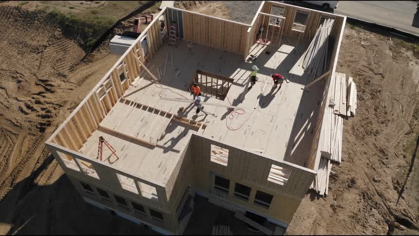 An aerial view of a construction site with workers framing the structure of a building