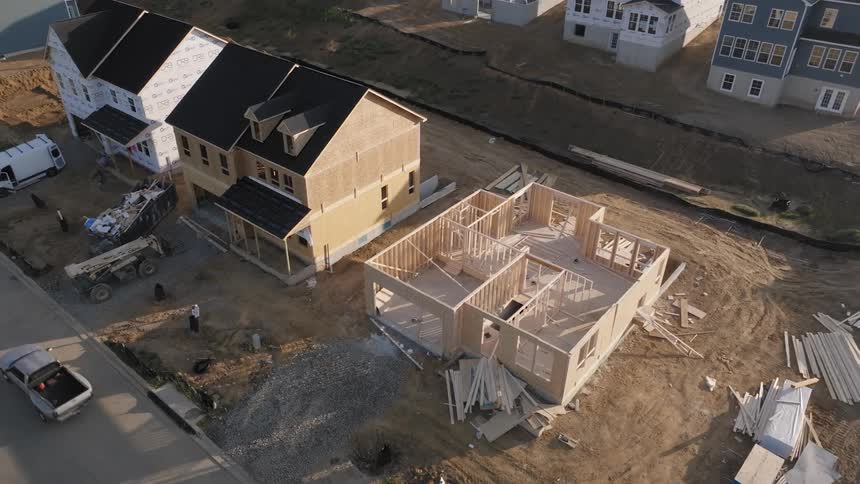 Aerial view of a residential construction site with two houses at different stages of completion