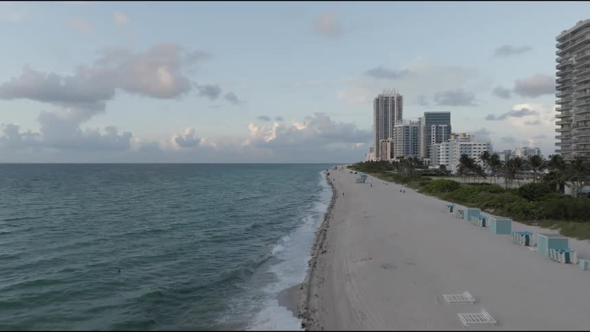 Aerial view of a beach with a long stretch of sand and the edge of a large building