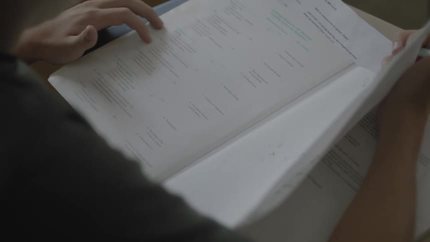 A male student pores through an ap biology lab manual at his desk in a classroom
