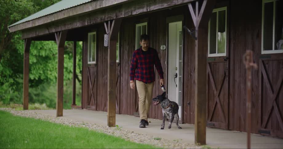 A man takes his dog out of the house