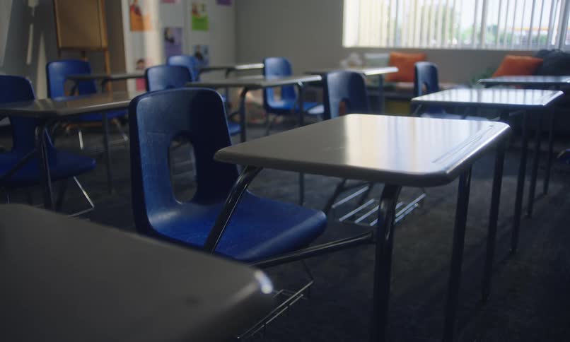 An empty classroom with individual desks and blue chairs
