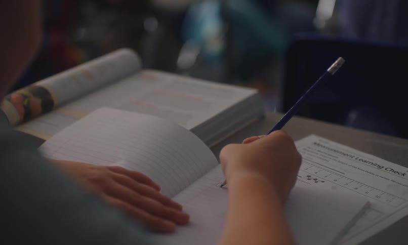 A student writing in a notebook during a lesson