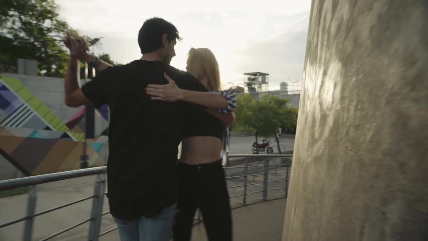 Man and woman dancing together in a hallway in an outdoor setting