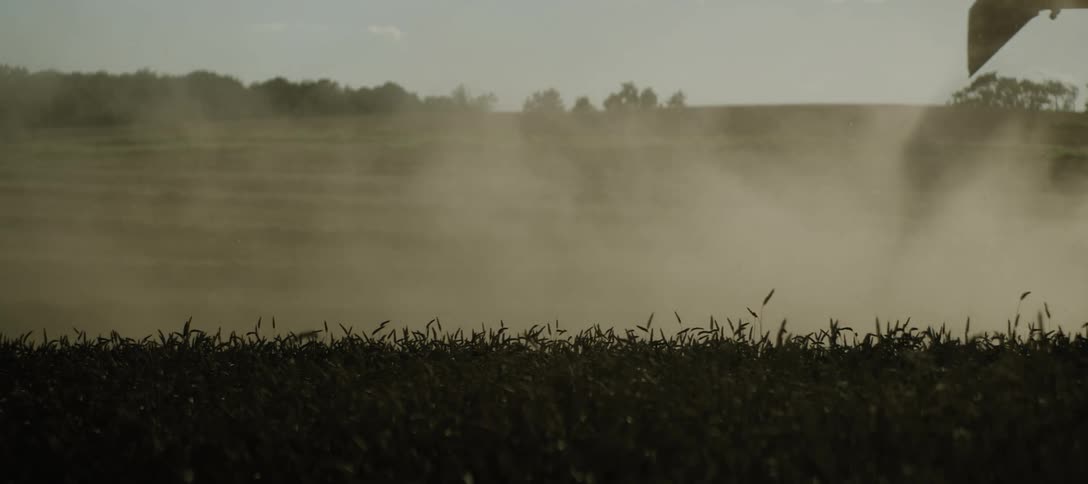 Silhouette of a combine harvester sowing a field at morning