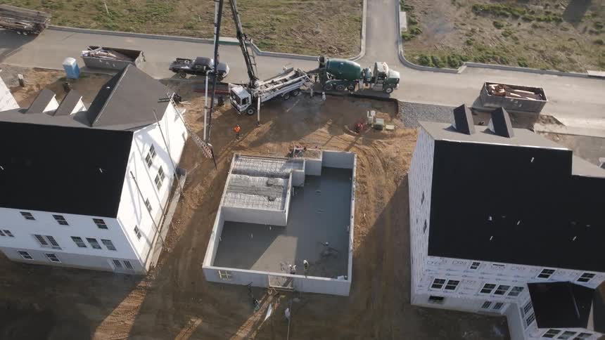 Aerial view of a concrete pump filling the foundations of a house being constructed in the neighborhood