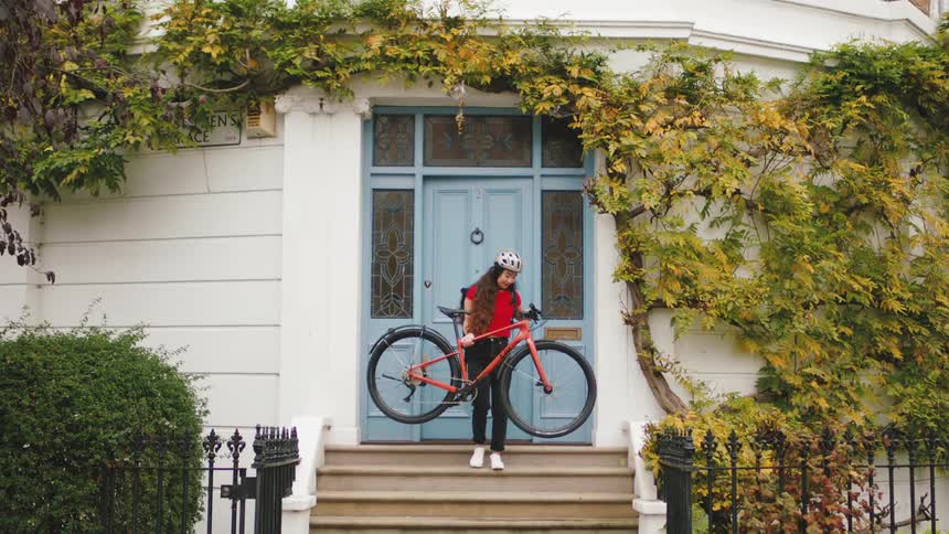 Woman leaving her house and going down the stairs with her bicycle