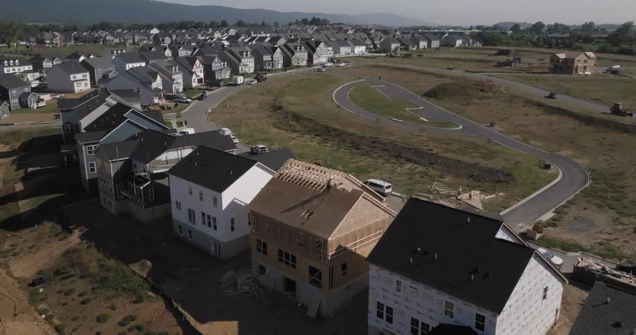 Aerial view of a person on the roof of a house under construction in a residential neighborhood