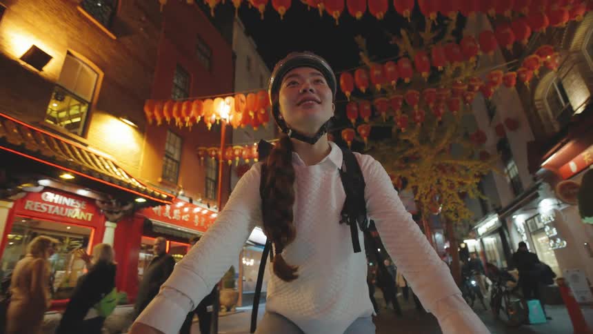 Portrait of a woman with a happy facial expression riding a bicycle in a city corridor with open shops and pedestrians