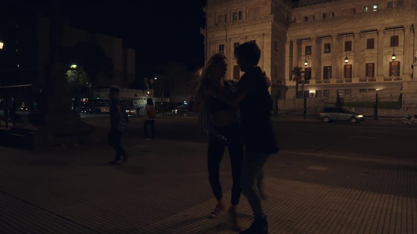 Silhouette of a young couple dancing on the city streets at night