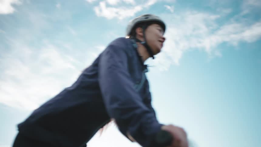 A cyclist riding a bicycle on a sunny day with a clear blue sky in the background