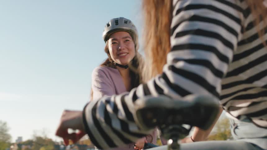 Two young women sitting on their bicycles talking