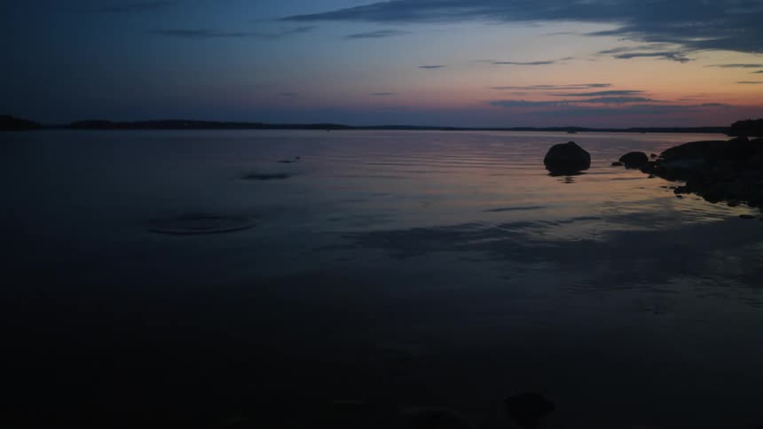 Stones skipping over the surface of a calm lake at sunset