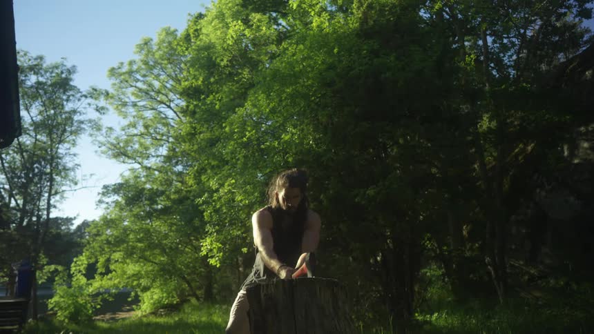 Man chopping wood with an axe on a woodstump in the forest