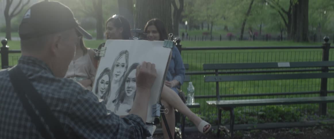 Women sitting on bench having themselves drawn by man in park