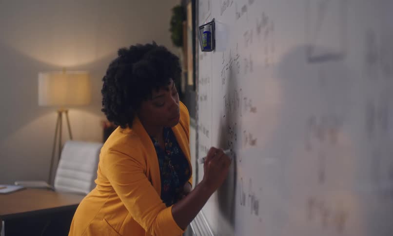 Teacher writing on a board in a classroom
