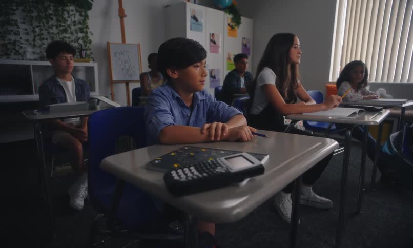 Students laugh while sitting at their desks in a classroom