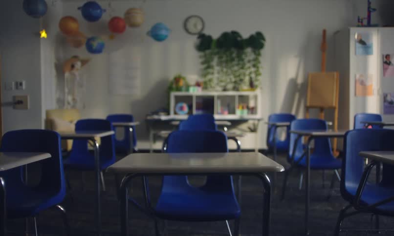 An empty classroom with small blue chairs and tables arranged neatly