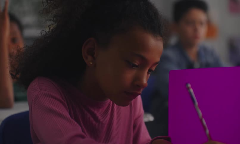 Portrait of a child sitting at a classroom desk writing