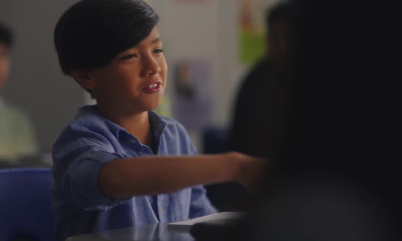Student raising his hand to answer question in a classroom