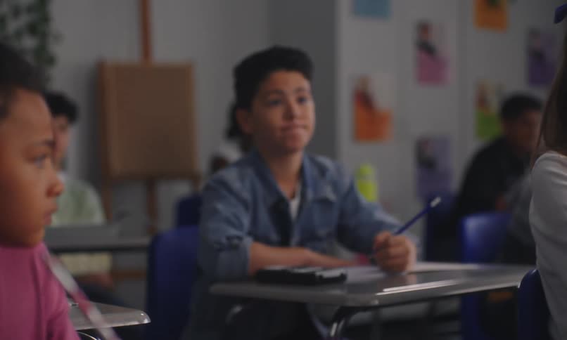 Students sitting in a classroom taking notes and listening to the teacher