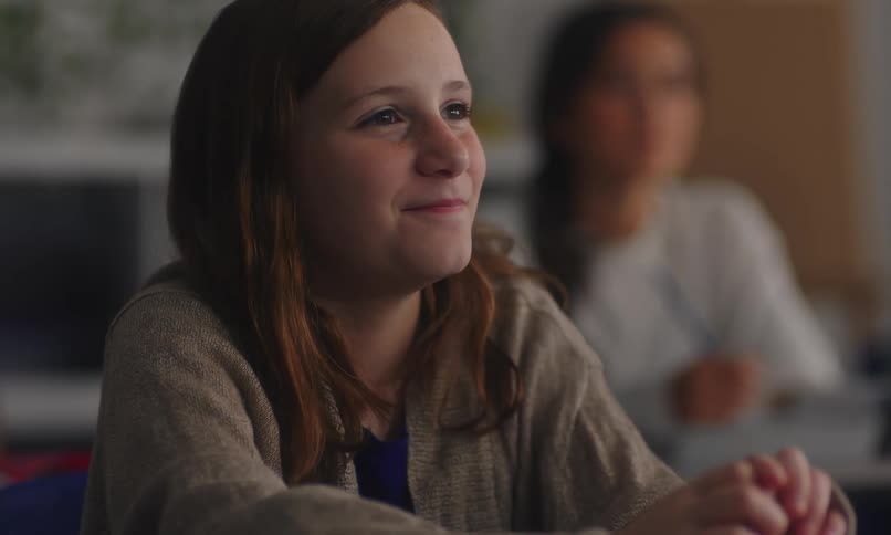 Student in classroom raising her hand