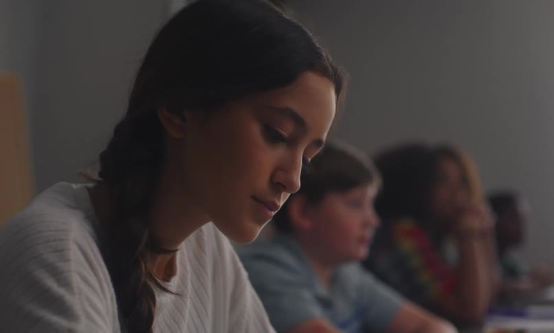 A group of students sitting on a classroom listening to a teacher