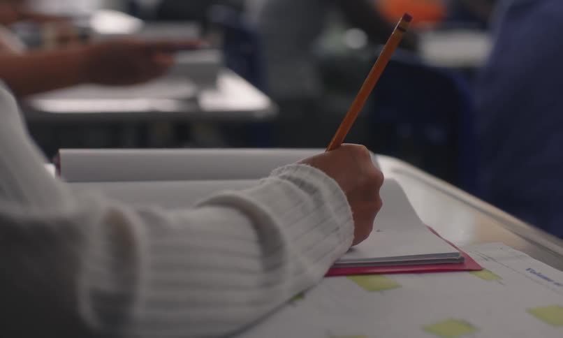 Hand holds a pencil over a sheet of paper