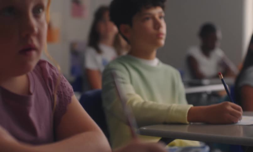 Students listen and take notes while sitting at their desks in the classroom