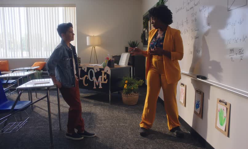 Boy paying attention to the teachers explanation in a classroom and on a whiteboard
