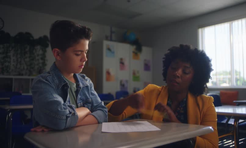 A teacher helps a student taking a test in the classroom